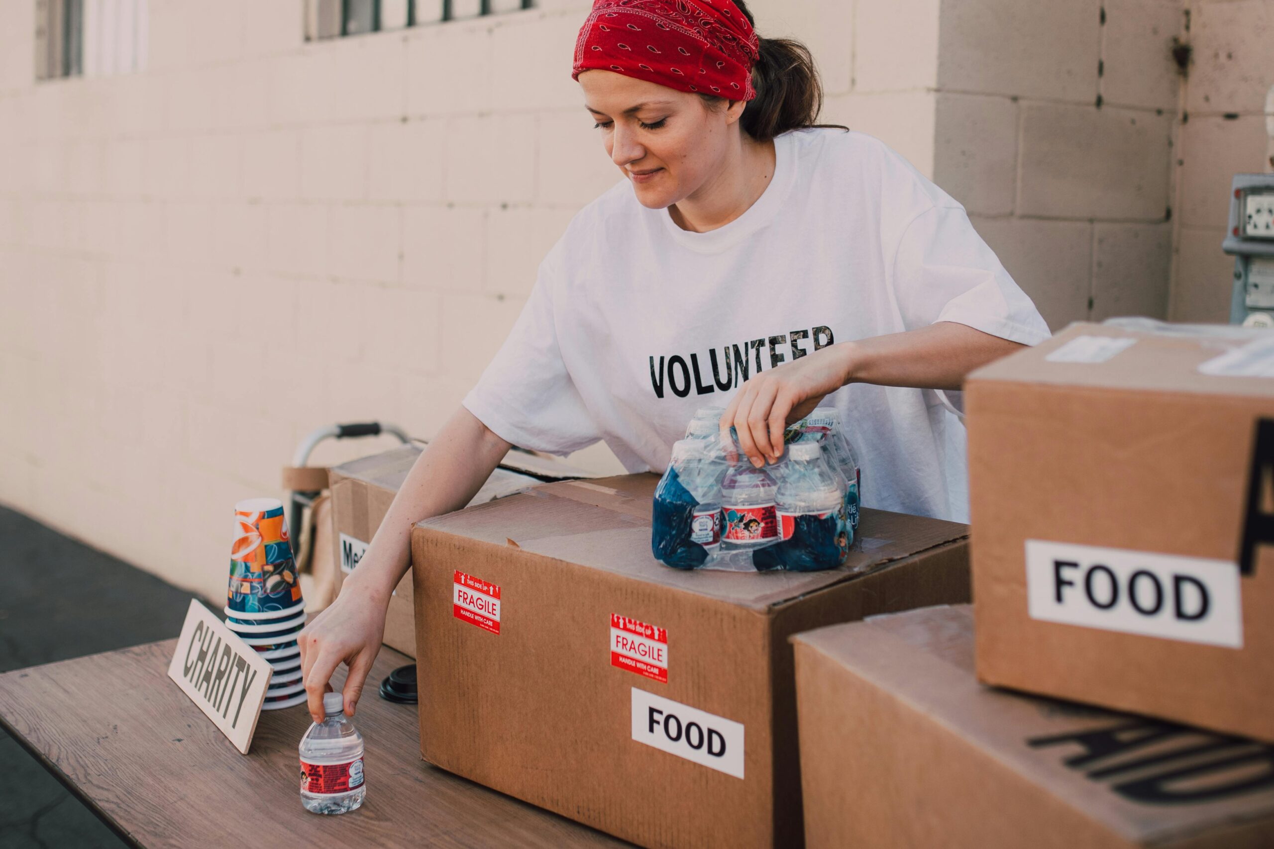 Woman volunteer sorting food and water for charity distribution at aid center.